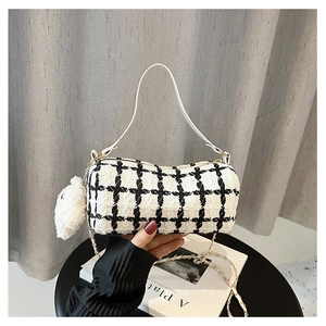 Detail of checkered cylinder bag with white leather handle and plush bear charm