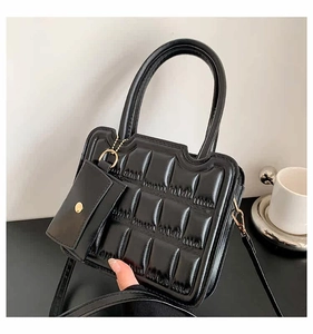 Close-up of black quilted leather crossbody bag with golden hardware and mini pouch