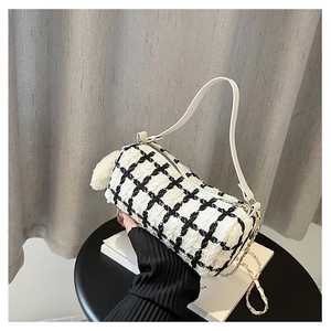 Detail of tweed checkered cylindrical handbag with gold chain and white fur ball pendant