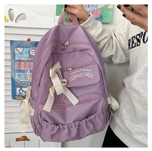 Detailaufnahme des lila Schulrucksacks mit weißer Schleife und mehreren Taschenfächern