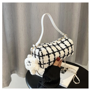 Detail of checkered barrel bag featuring woven pattern and plush bear charm