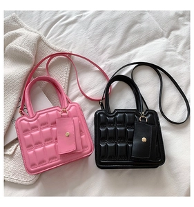 Detail of pink and black quilted square bags with matching mini coin pouches on soft fabric