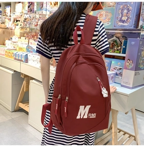 Detail of burgundy vintage backpack with white letter printing and bear charm