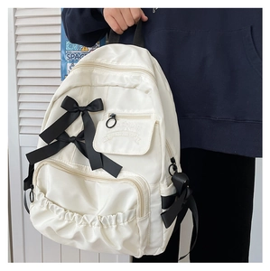 Detail eines weißen Rucksacks mit großen schwarzen Schleifen und Fronttaschen