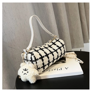 Detail of checkered tweed barrel bag featuring a plush star charm and gold chain strap
