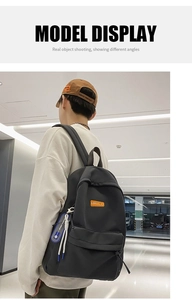 Close-up of black nylon backpack featuring orange logo patch and blue ribbon detail