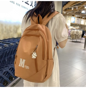 Detailed back view of a brown vintage backpack with a cute bear charm and large capacity