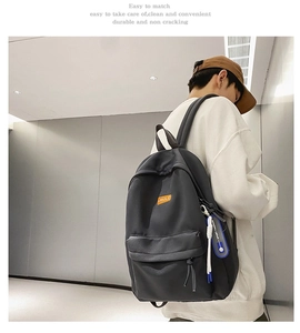 Detailed back view of a minimalist black backpack featuring sport charms and orange logo