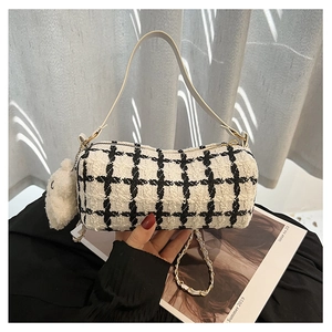 Detail of checkered tweed barrel bag with chain strap and cute plush bear charm