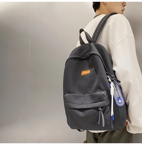 Detail showing charcoal grey minimalist backpack with orange label and blue sport strap