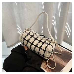 Detailed view of black and white tweed crossbody bag with metal chain strap