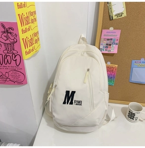 Detail view of a white minimalist school backpack with M RMI logo in a dorm setting
