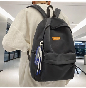 Close-up of black backpack texture with MRMILID brand tag and blue sport fashion pendant