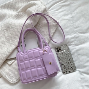 Purple quilted faux leather handbag with mini pouch and gold hardware on white fabric