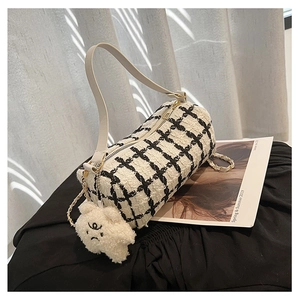 Detail of tweed cylinder handbag featuring black white checks and plush bear charm