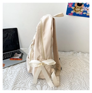 Detailansicht des cremeweißen Nylon-Rucksacks mit großer Schleife und Seitentasche