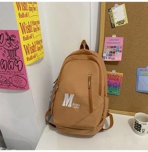 Detail view of khaki nylon backpack featuring white M RMI letter embroidery and front pocket
