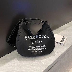 Close-up of black canvas crossbody bag with white typography on a marble surface