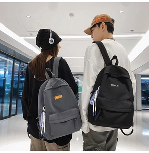 Detail view of dark grey and black nylon backpacks with MRMILID brand tag on two models