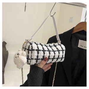 Detail view of black and white tweed barrel bag with chain strap and teddy bear charm