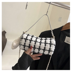 Detail of black and white tweed cylinder bag with furry charm and metal chain