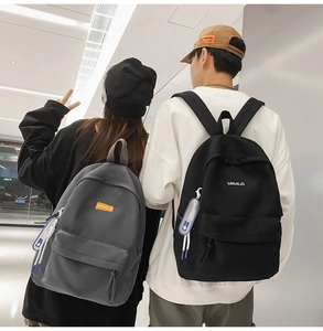 Street style view of durable nylon backpacks in grey and black on male and female models