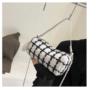Detail of tweed baguette bag featuring dual white leather and gold chain straps