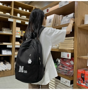 Black vintage college style backpack with white M logo and cute bear charm in a shop