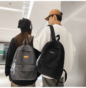 Close-up of minimalist black and grey nylon backpacks with sport fashion pendants