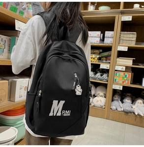 Close-up of black canvas student backpack with bear keychain and large logo print
