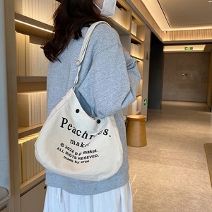 Off-white canvas crossbody tote bag with adjustable strap and black letter print
