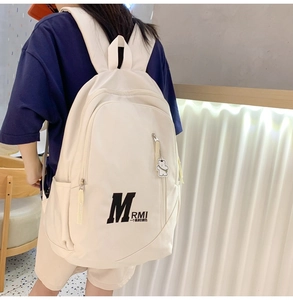 Detailed back view of a minimalist cream canvas backpack featuring aesthetic lettering