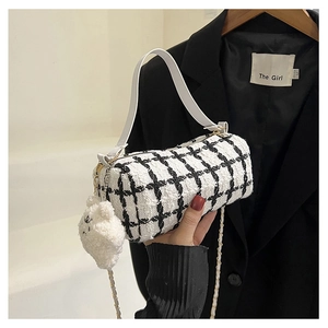 Detail of tweed checkered barrel bag with chain strap and cute white plush sheep charm