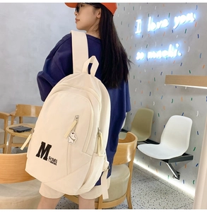 Close-up of beige vintage college style backpack with cute bear pendant and large capacity