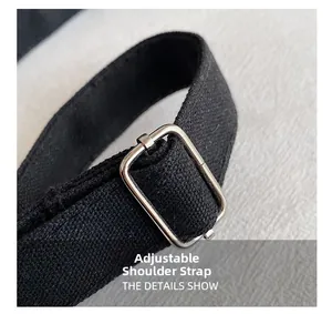 Macro detail of the adjustable black canvas shoulder strap with a silver metal buckle