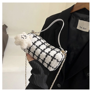Detail of checkered tweed barrel bag with gold chain and white star plush charm