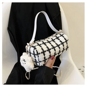 Close-up of black and white tweed cylinder bag with white leather strap and plush charm