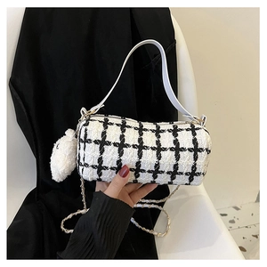 Close-up of a plaid cylinder bag with metal chain strap and cute white bear charm