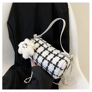 Detail of checkered woven cylinder bag with plush star charm and dual straps