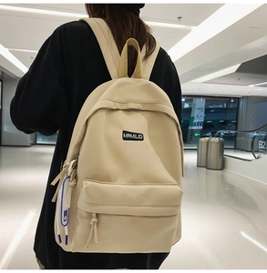 Detail view of the cream canvas backpack featuring the MRMILID brand woven label and texture