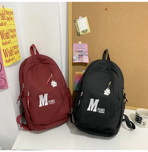 Detail of burgundy and black vintage backpacks with M letter and cute bear pendant
