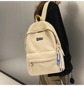 Detail of minimalist beige backpack featuring side zipper with blue silicone sport charm