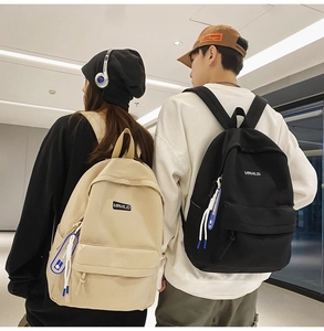Minimalist nylon school backpack in black and beige shown on models in modern city setting