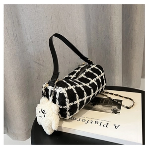 Detail of tweed barrel bag with gold chain strap and cute white teddy bear charm