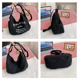 Detailed views of a black canvas crescent bag featuring white artistic lettering and side pockets