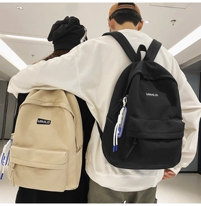 Detailed view of black and khaki canvas backpacks worn by models in a minimalist setting