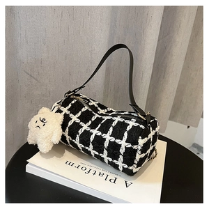 Detail of checkered barrel bag with plush star charm and black leather strap on a stool