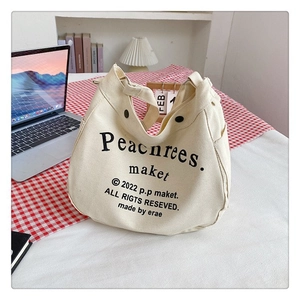 Detail of off-white canvas tote bag featuring black artistic text on a checkered table