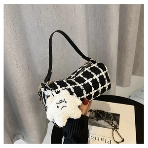 Close-up of black and white tweed cylinder bag with gold chain and star plush charm