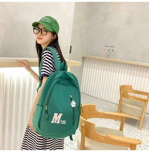 Detail view of green vintage school backpack with a cute white bear pendant charm